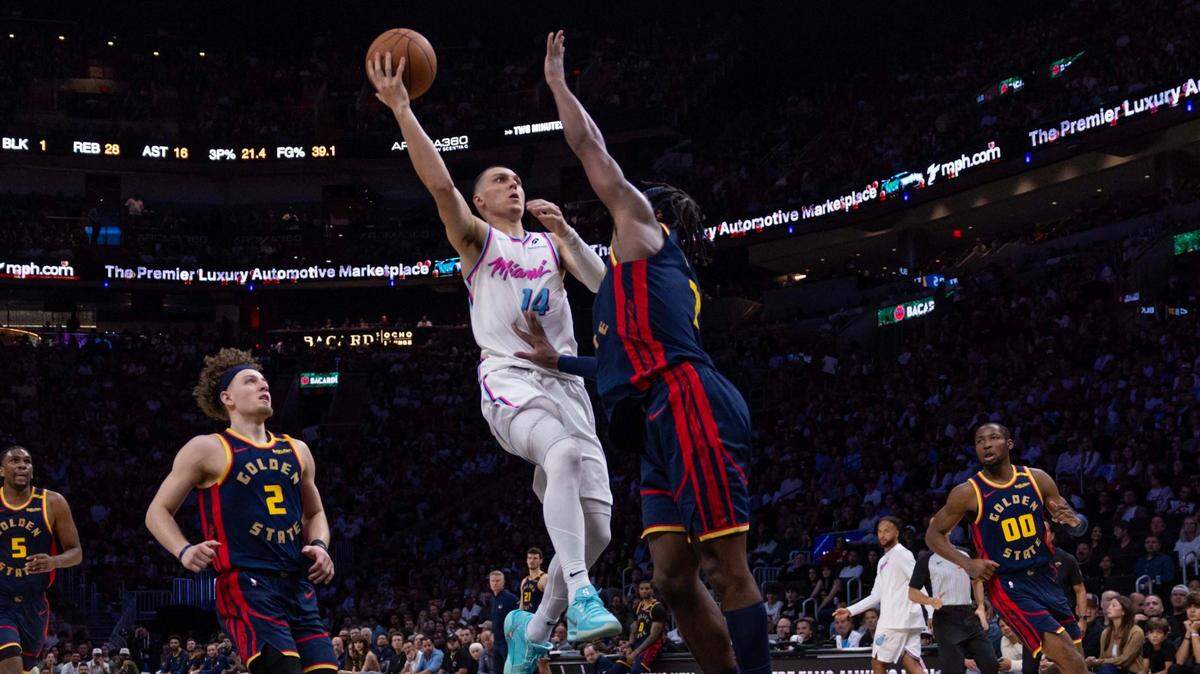 El jugador del Heat Tyler Herro tira al aro ante la marca de Kevon Looney, de los Warriors de Golden State, en el partido celebrado el 25 de marzo de 2025 en Miami.