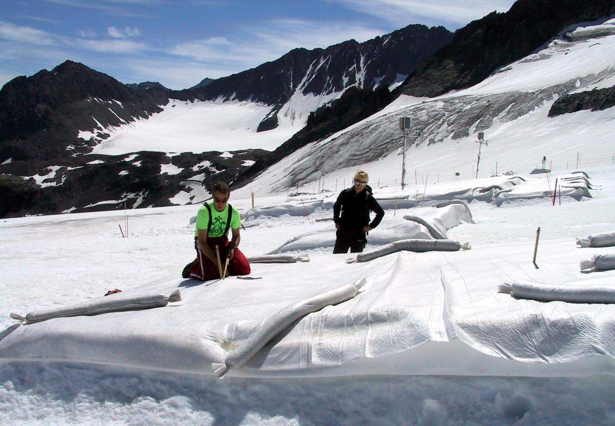 Marc Olefs, (izq.), y Andrea Fischer, investigadores de Innsbruck University, en un campo de nieve cubierto con polietileno. La idea es atrapar el calor de la atmósfera o reflejar la luz del sol de vuelta al espacio.