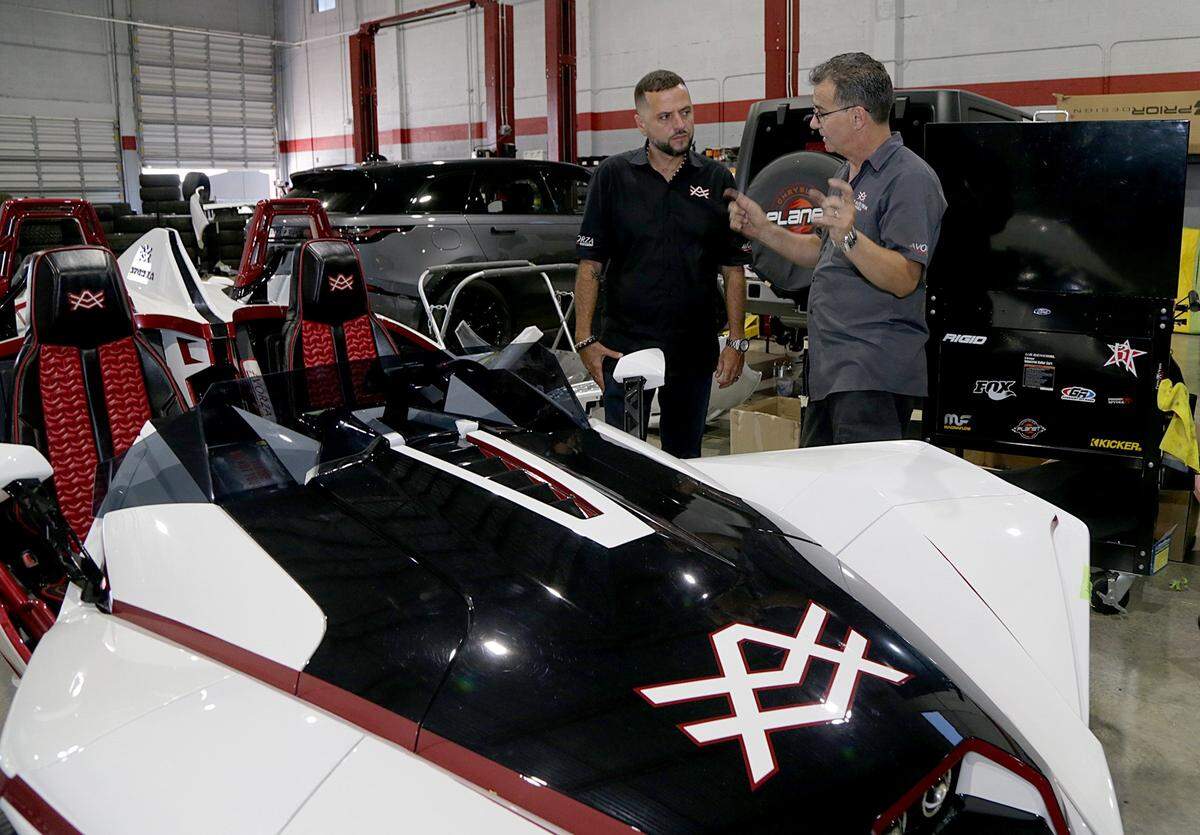 El gurú de los autos Alex Vega, dueño de The Auto Firm, habla con Orelbis Darias (derecha), uno de los técnicos del negocio, dedicado a personalizar automóviles caros.