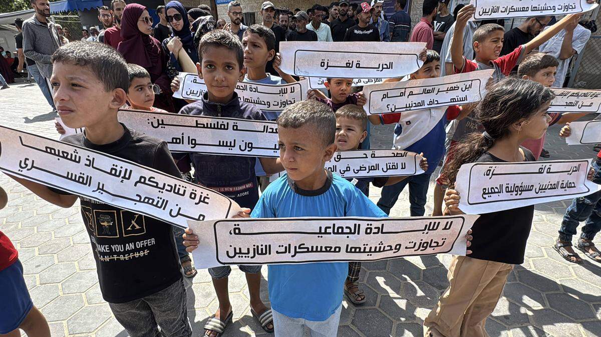 Decenas de niños palestinos participan en una protesta contra la guerra en Gaza, y el bloqueo de la llegada de alimentos, medicinas y ayuda humanitaria, el martes 19 de agosto de 2025, en la región central de la Franja de Gaza.