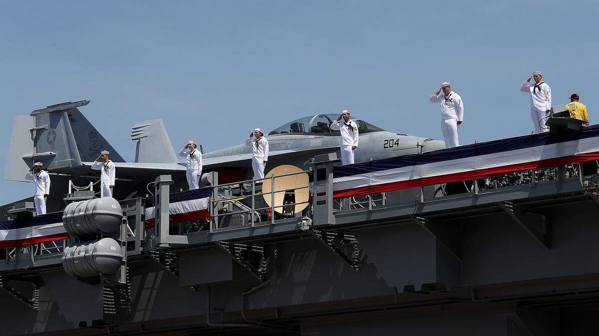 Los marineros y la tripulación rinden un saludo a bordo del USS Gerald Ford mientras el barco se activa durante las ceremonias de puesta en servicio el 22 de julio de 2017, en la Estación Naval de Norfolk, Virginia.
