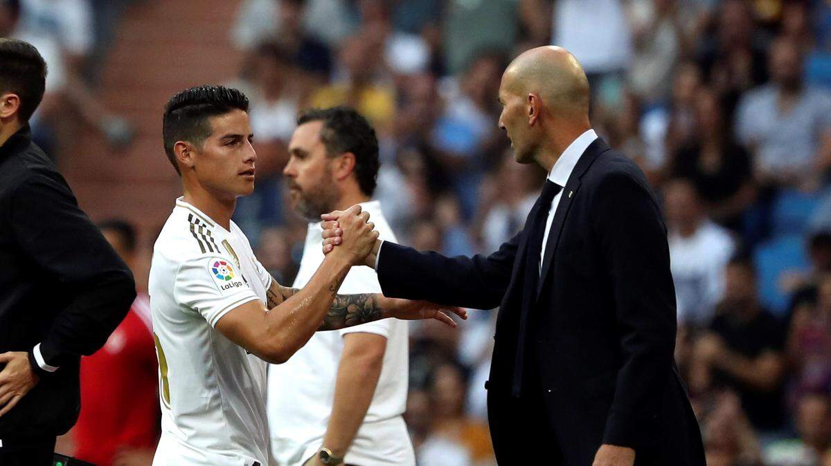 El jugador del Real Madrid James Rodríguez saluda a su entrenador Zinedine Zidane tras salir sustituido en el partido ante el Real Valladolid, disputado en el Estadio Santiago Bernabéu, en Madrid.