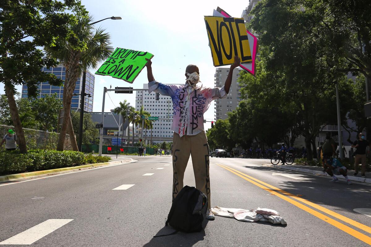 A protester holding signs is seen marching in Downtown Miami, Sunday, may 30, 2020