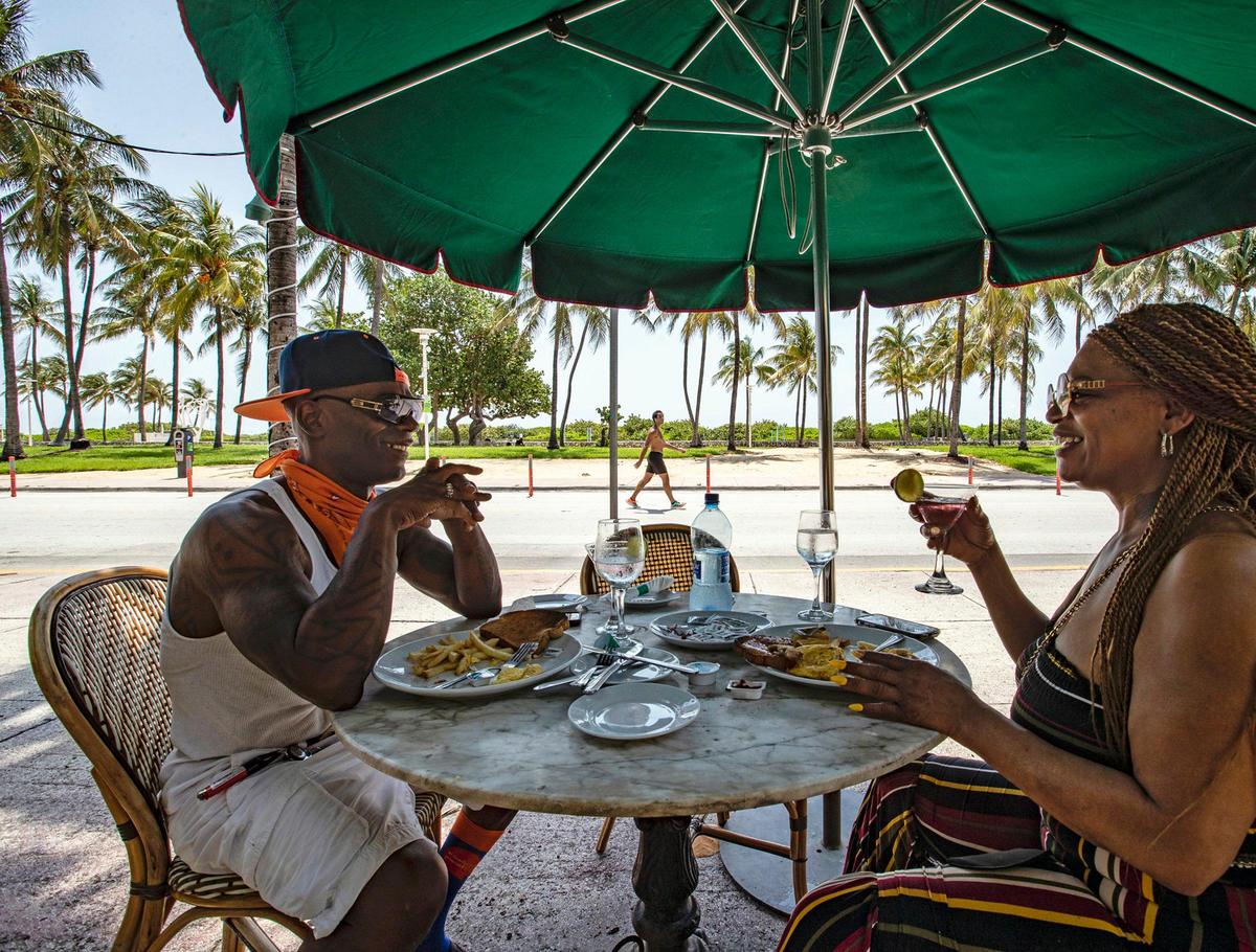 In this file photo from May 27, 2020, Freddie Beard and his wife Debra Beard enjoy breakfast at the News Cafe along Ocean Drive on South Beach.