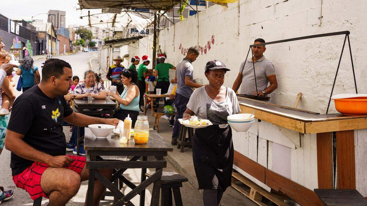 Una mujer sirve comida en un restaurante popular en el barrio Sarría de Caracas, Venezuela, el 10 de diciembre de 2023.