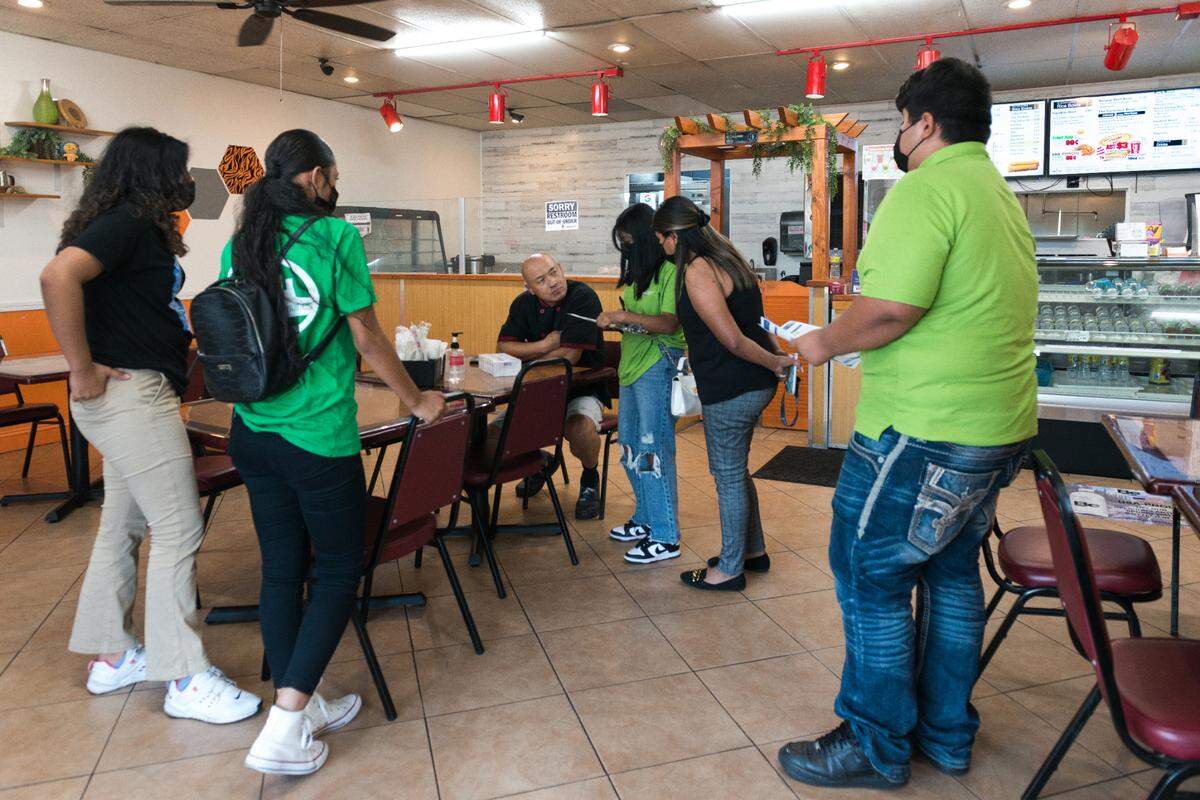 Jóvenes entregan pruebas de covid y folletos informativos a Chris Vang, propietario de Tiger Bite Bowls, un restaurante de fusión asiática en Fresno, California. Los jóvenes han sido capacitados como educadores de salud para promover las vacunas covid.