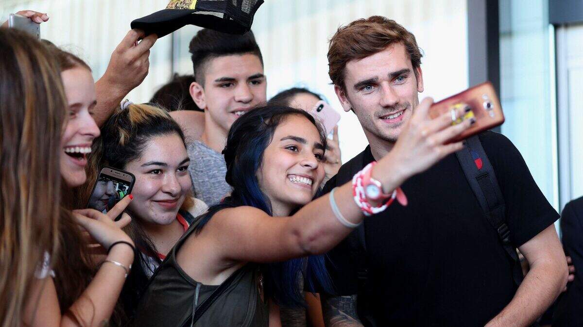 El futbolista francés Antoine Griezmann (der.) atiende a aficionados uruguayos a su llegada a Montevideo, Uruguay, el 26 de diciembre de 2018.