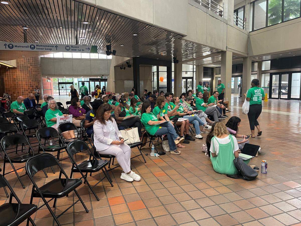 South Florida residents have organized against Miami-Dade County’s plan to build the nation’s largest trash incinerator near their communities. At a September meeting of the county’s board of commissioners, many protesters dressed in green T-shirts with a simple message printed in white, “MIRAMAR SAYS NO TO INCNERATOR.” They filled the commission’s chambers and overflowed into the atrium, where they watched the meeting on a television screen. (Daniel Chang/KFF Health News)
