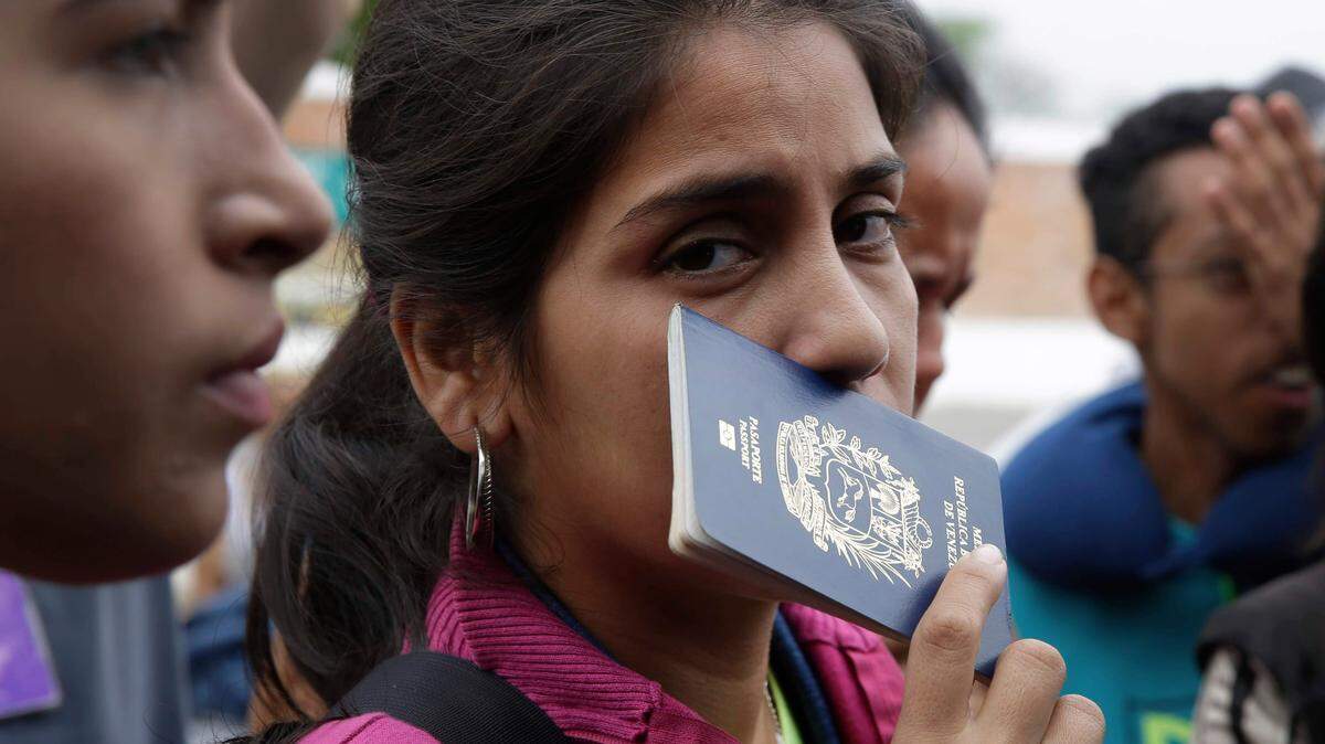 Fotografía de archivo de una venezolana sosteniendo su pasaporte.