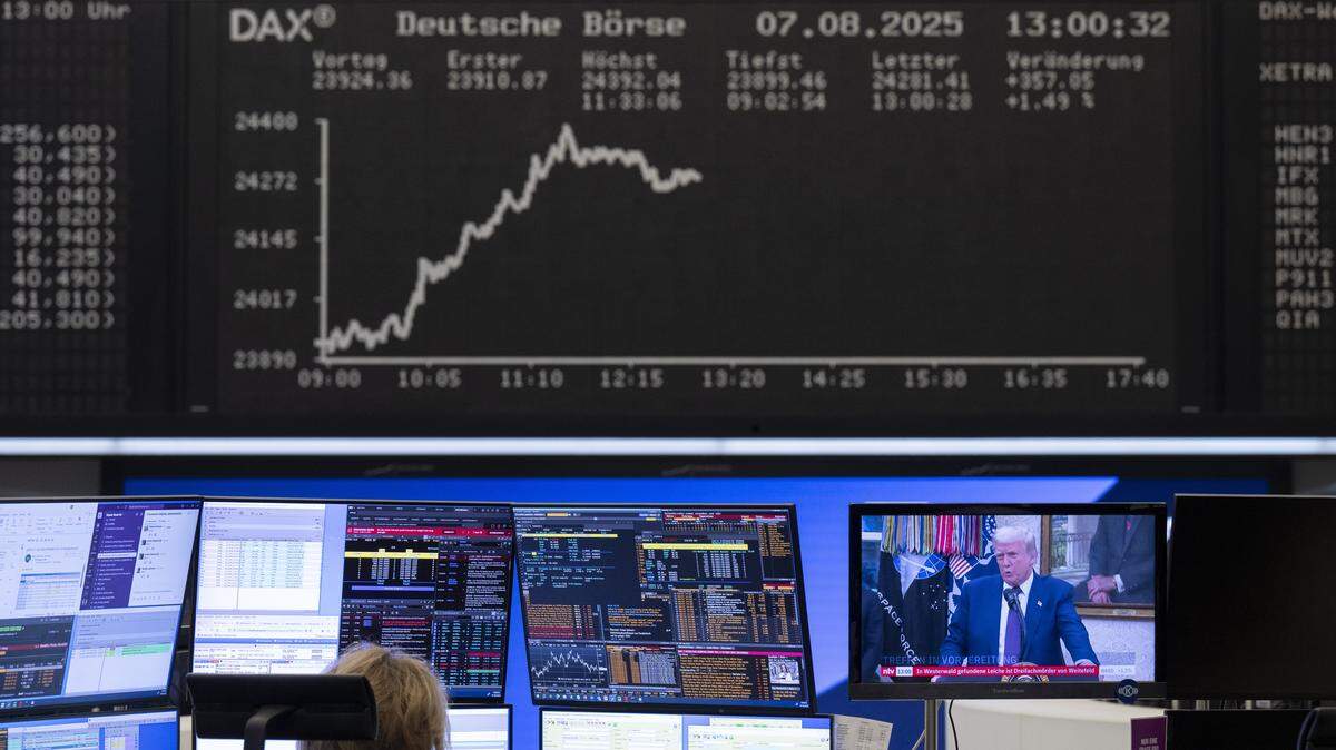 Un analista de mercado monitorea las transacciones en la Bolsa de Valores de Frankfurt, Alemania, mientras el presidente de EEUU, Donald Trump, aparece en la pantalla de la television, el jueves 7 de agosto de 2025.