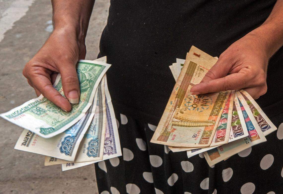 In this 2013 photo a Cuban shows Cuban Pesos in one hand and Convertible Pesos in the other. The government began to eliminate the dual currency system in January.