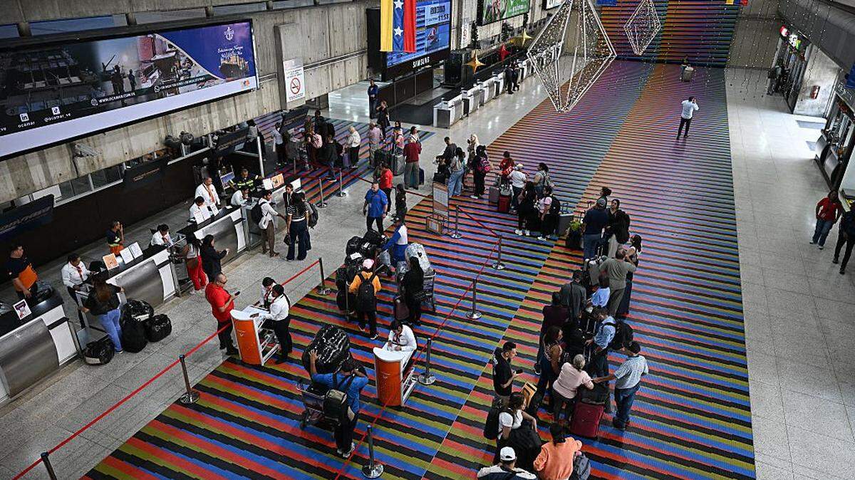 Passengers queue at counters at Simon Bolivar International Airport in Maiquetia, La Guaira State, Venezuela, on November 27, 2025. Venezuela's decision to ban foreign airlines that stopped flying to the Caribbean country over concerns about US military activity was branded "disproportionate" on Thursday as thousands of passengers scrambled to save their travel plans. (Photo by Federico PARRA / AFP via Getty Images)