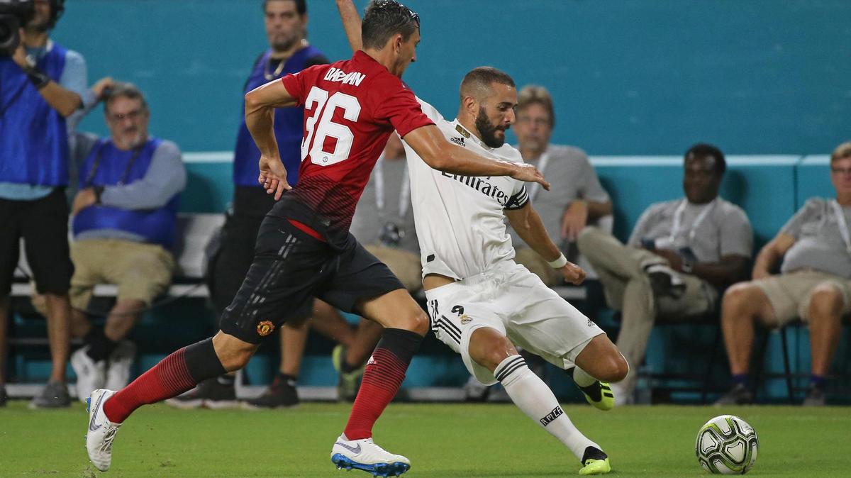 Karim Benzema, autor del gol del Real Madrid (der.) dispara a puerta ante la marca de Matteo Darmian, quien dio el pase en el primero del Manchester United este 31 de julio por la International Champions Cup en el Hard Rock Stadium en Miami Gardens.