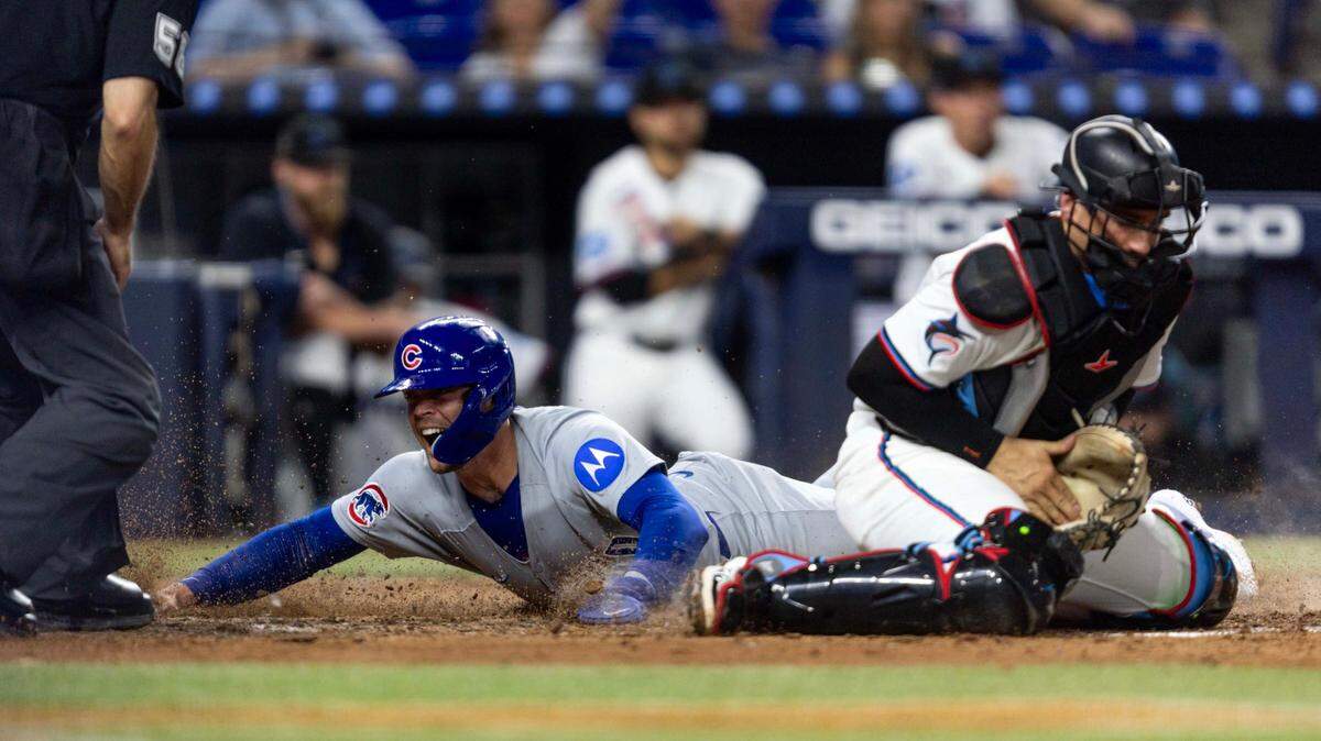 El pelotero de los Cachorros de Chicago Nico Hoerner anota una carrera ante el receptor de los Marlins Nick Fortes, en el sexto inning del partido celebrado el 20 de mayo de 2025 en Miami.
 