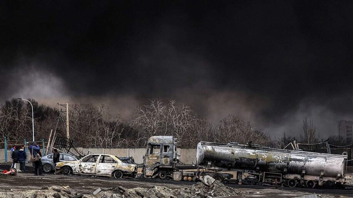 Una nube de humo oscuro envuelve vehículos destruidos cerca de un incendio en curso tras un ataque aéreo nocturno contra la refinería de petróleo de Shahran, en el noroeste de Teherán, el 8 de marzo de 2026.