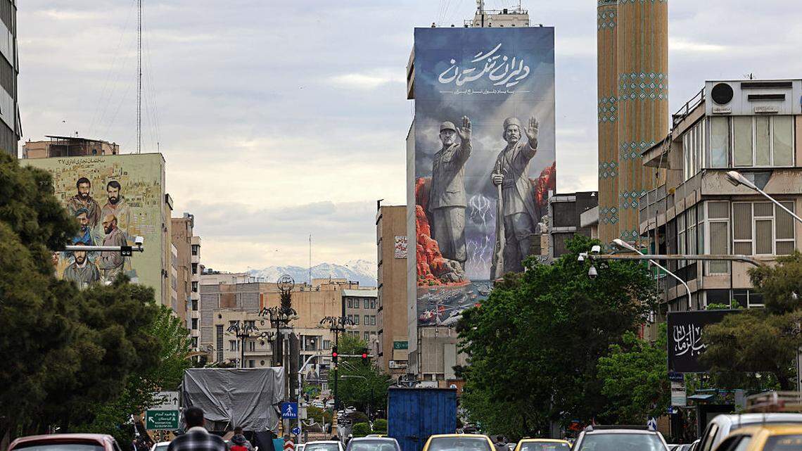 Los transeúntes pasan en coche frente a una valla publicitaria gigante que hace referencia al “estrecho de Ormuz”, a lo largo de una concurrida calle de Teherán, el domingo 19 de abril de 2026.