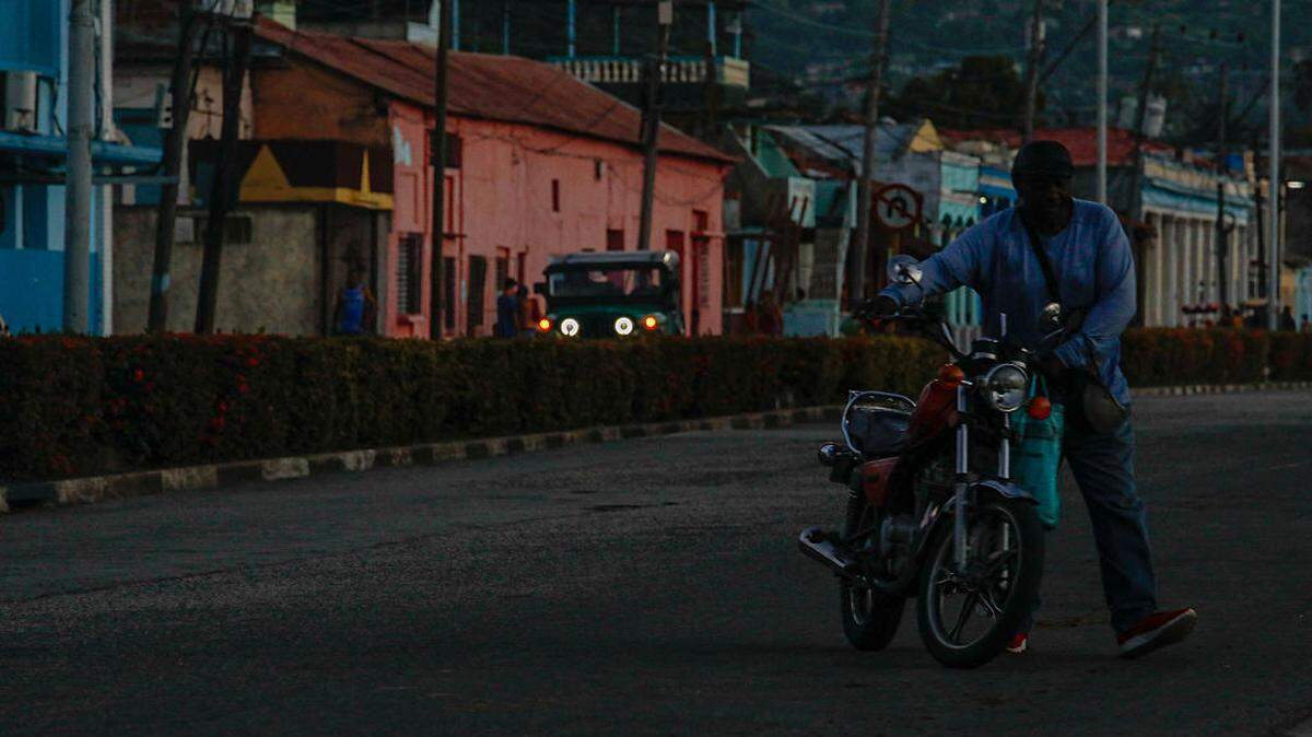 Un hombre traslada una motocicleta durante un apagón en Santiago de Cuba el 14 de mayo de 2026.