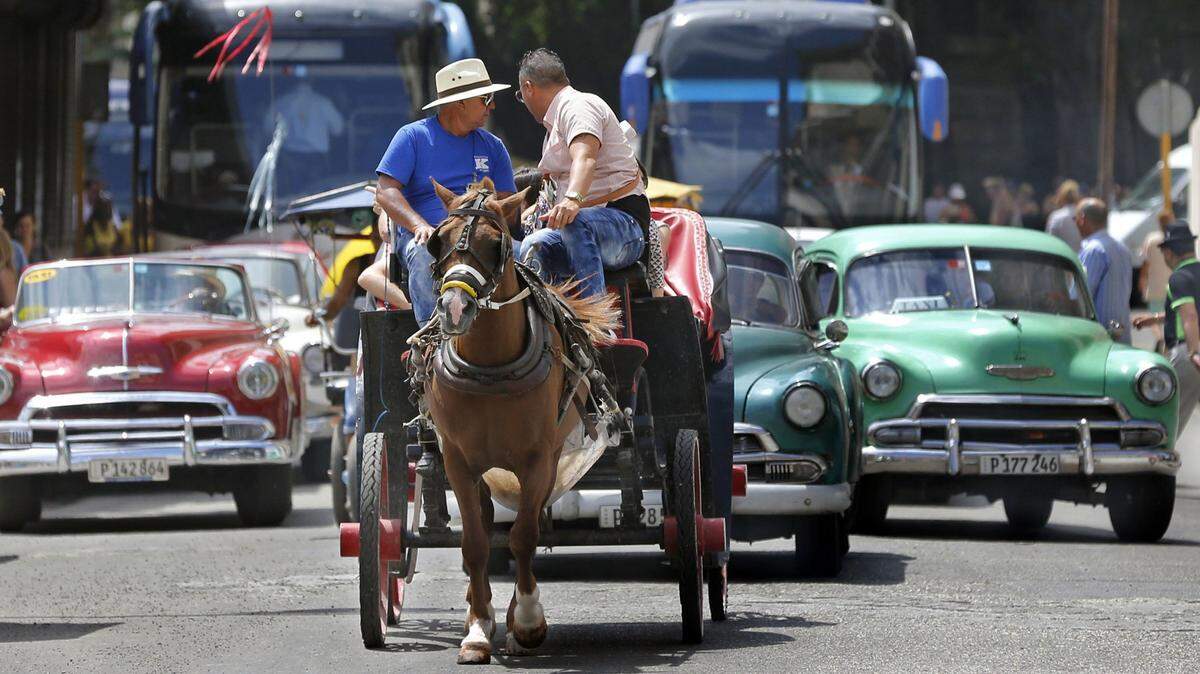 Autobuses turísticos comparten la vía con autos clásicos estadounidenses y una carreta tirada por caballos en La Habana, Cuba, en marzo de 2016.
