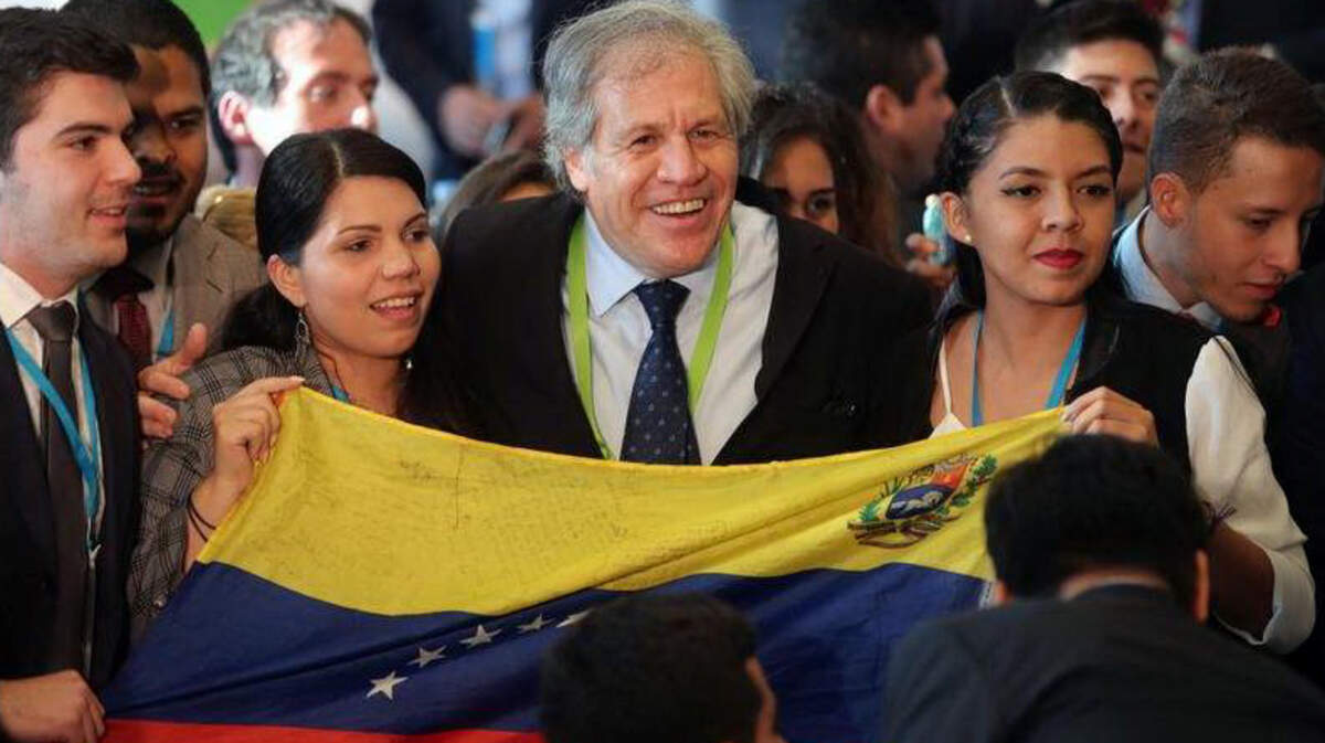 El secretario general de la Organización de Estados Americanos (OEA), Luis Almagro (c), posa para una foto con dos jóvenes venezolanas y una bandera de ese país el miércoles 11 de abril de 2018, durante el Foro de los Jóvenes, una de las reuniones preparatorias para la Cumbre de las Américas, en Lima (Perú).