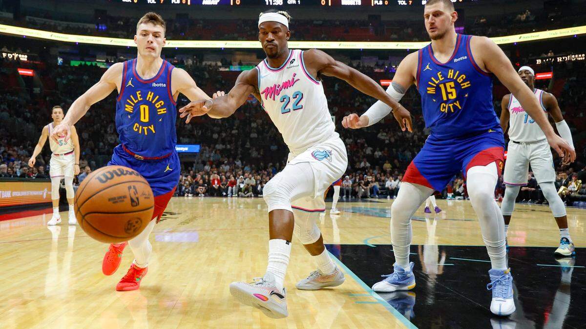El delantero del Heat, Jimmy Butler (22), lucha por la peloata ante el armador de los Nuggets, Christian Braun (0), y el pívot Nikola Jokic (15), en el partido de baloncesto de la NBA celebrado el 17 de enero de 2025 en el Kaseya Center en Miami, Florida.
