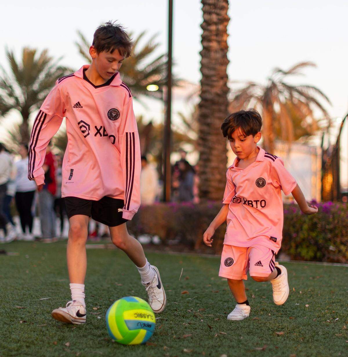 Kellen Haleua (izq.) y Ciro Izzo, de 12 y 6 años respectivamente, juegan con un balón afuera del Chase Stadium antes del esperado encuentro entre el Inter Miami y el Real Salt Lake, en la inauguración de la nueva temporada de la MLS el 21 de febrero de 2024 en Fort Lauderdale, Florida.
