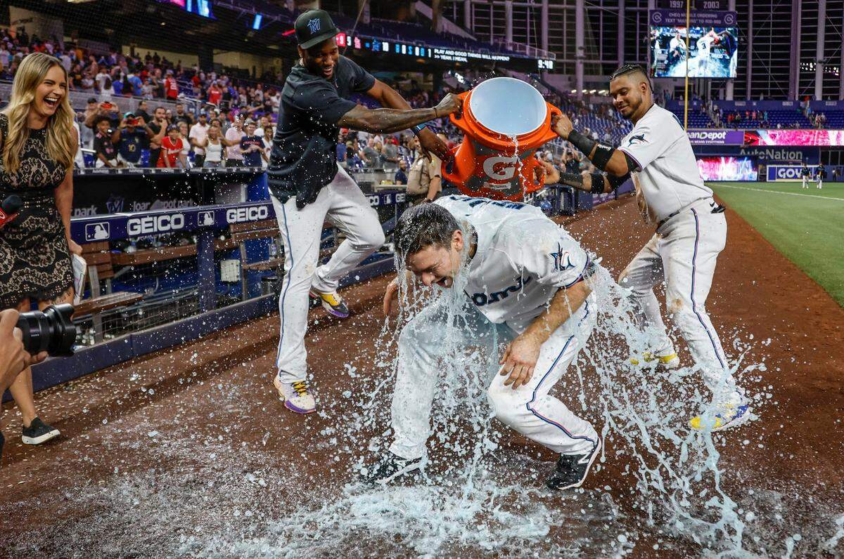 El torpedero de los Marlins Joey Wendle es bañado por sus compañeros de equipo Jorge Soler (izq.) y Luis Arráez tras la victoria del equipo en el noveno inning ante los Cardenales de San Luis, en el partido celebrado el 5 de julio de 2023 en Miami.