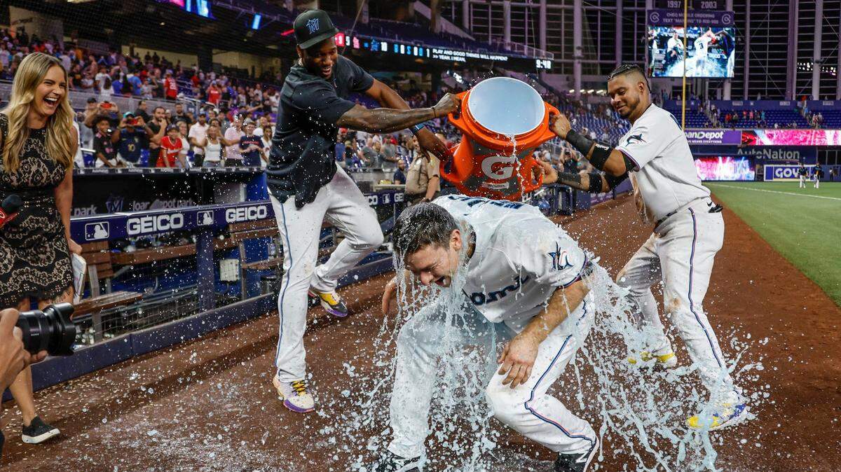 El torpedero de los Marlins Joey Wendle es bañado por sus compañeros de equipo Jorge Soler (izq.) y Luis Arráez tras la victoria del equipo en el noveno inning ante los Cardenales de San Luis, en el partido celebrado el 5 de julio de 2023 en Miami.