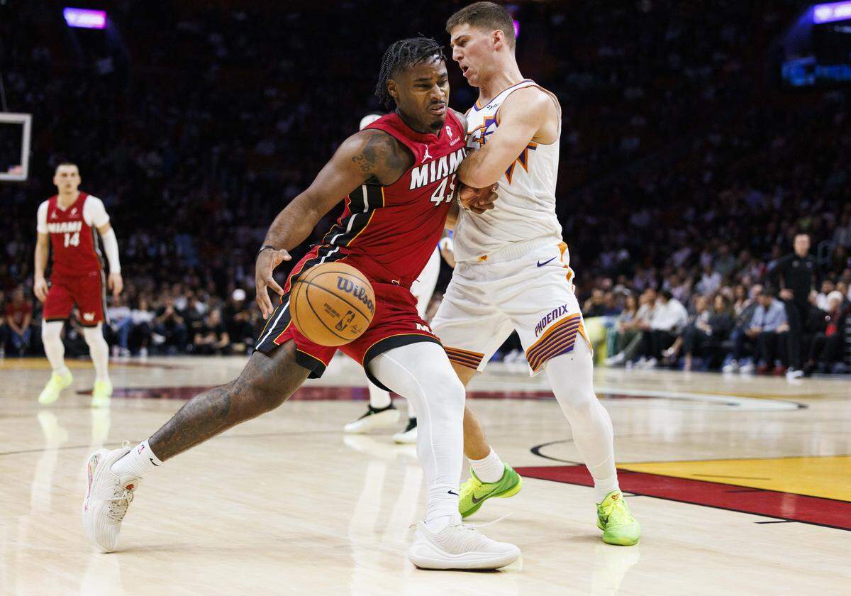 El jugador del Heat Davion Mitchell (izq.) entra al aro ante la marca de Collin Gillespie, de los Suns de Phoenix, en el partido celebrado el 13 de enero de 2026 en Miami, Florida.