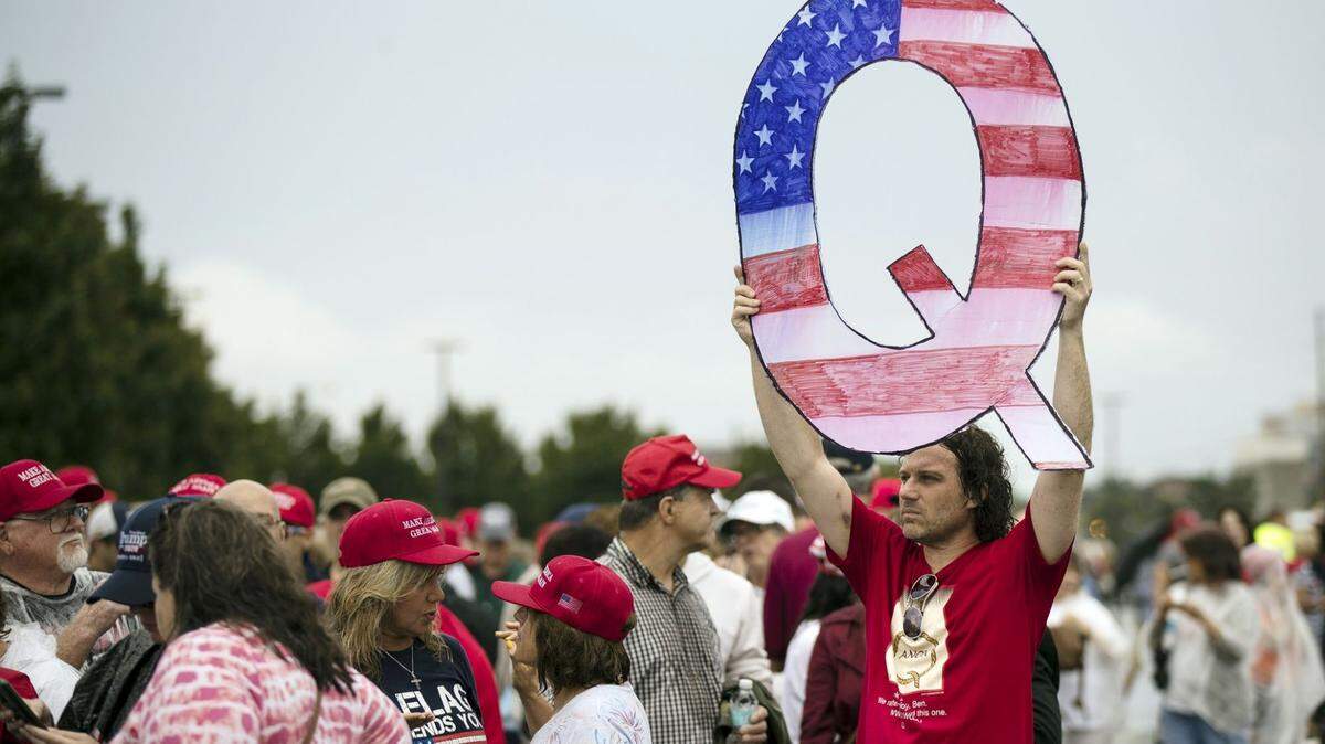 Un hombre sostiene un letrero con la ‘Q’ mientras espera ingresar a un mitin del presidente Trump en Pensilvania.