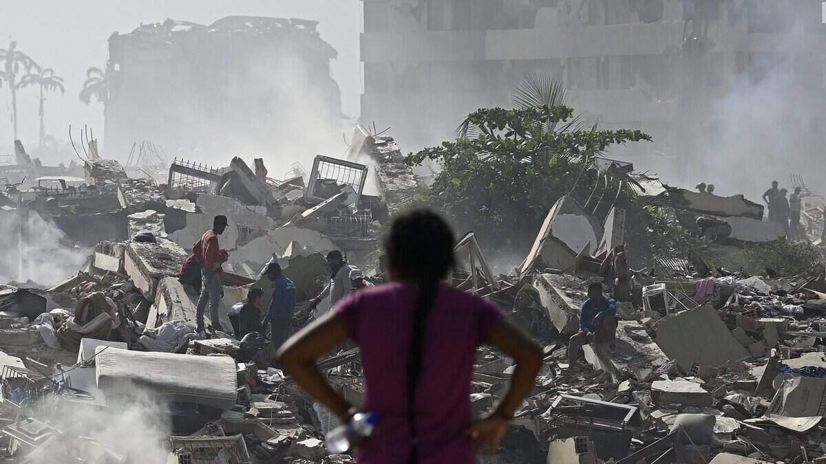A woman looks at the destruction as people search through the rubble of collapsed buildings following a twin earthquake in Caraballeda, La Guaira State, about 40 km northeast of Caracas, on June 25, 2026. The death toll from twin quakes, measured at magnitudes 7.2 and 7.5, has risen to at least 188, with more than 1,520 others injured, top lawmaker Jorge Rodriguez reported, while residents continue searching for missing relatives. (Photo by Federico PARRA / AFP via Getty Images)
