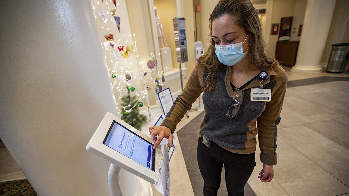 La intérprete Ana María Ríos Velez muestra la pantalla de una aplicación en la entrada principal del hospital Brigham and Women’s de Boston. Tiene una función multilingüe para comunicarse mejor con los pacientes y el personal que no habla inglés.