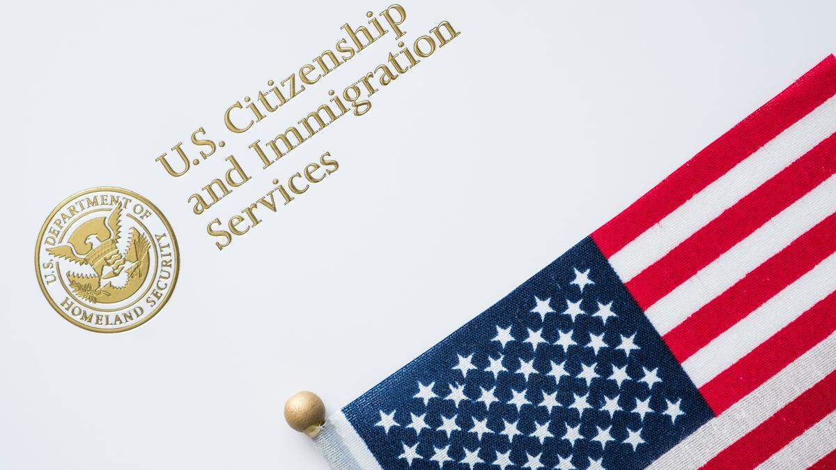 Un sobre del Servicio de Ciudadanía e Inmigración junto a la bandera de Estados Unidos.
