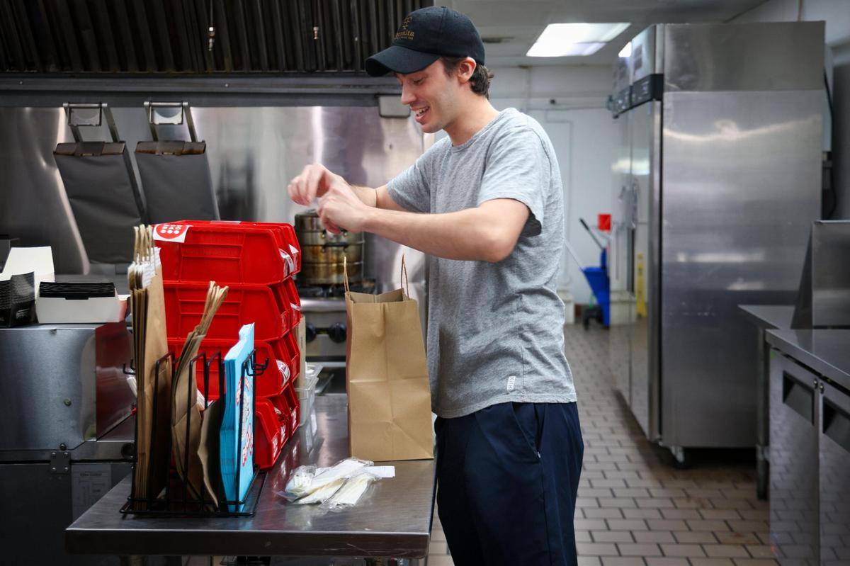 Cem Kinay prepara un pedido para recoger después de ser cocinado el chef robótico de Better Days. El negocio atiende a los vecinos y oficinas de los alrededores con comida para llevar y entrega a domicilio.