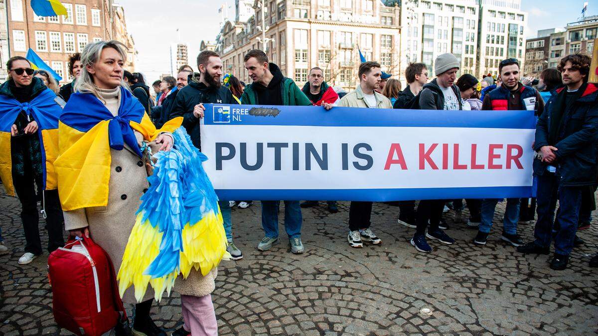 Miles de ucranianos, exsoldados y neerlandenses se congregan en Amsterdan, Países Bajos, para exigir un fin a la invasión rusa de Ucrania, el domingo 23 de febrero de 2025. La pancarta dice “Putin es un asesino”.