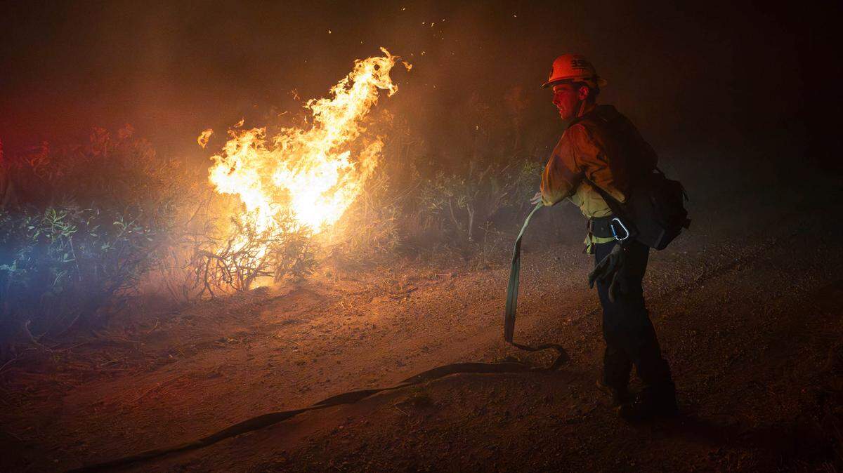 Un bombero de Cal prepara una manguera de agua para apagar incendios de matorrales. El Post Fire consume Gorman, California. El incendio ha consumido un total de 10.502 acres según el departamento de bomberos. (Foto de Jon Putman / SOPA Images/Sipa USA)