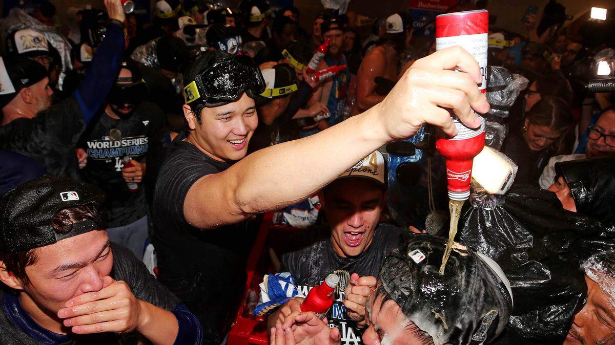 La estrella de los Dodgers de Los Angeles Shohei Ohtani (centro) celebra en el vestuario con sus compañeros luego de vencer a los Yankees y proclamarse campeones de la Serie Mundial, el 30 de octubre de 2024 en Nueva York.