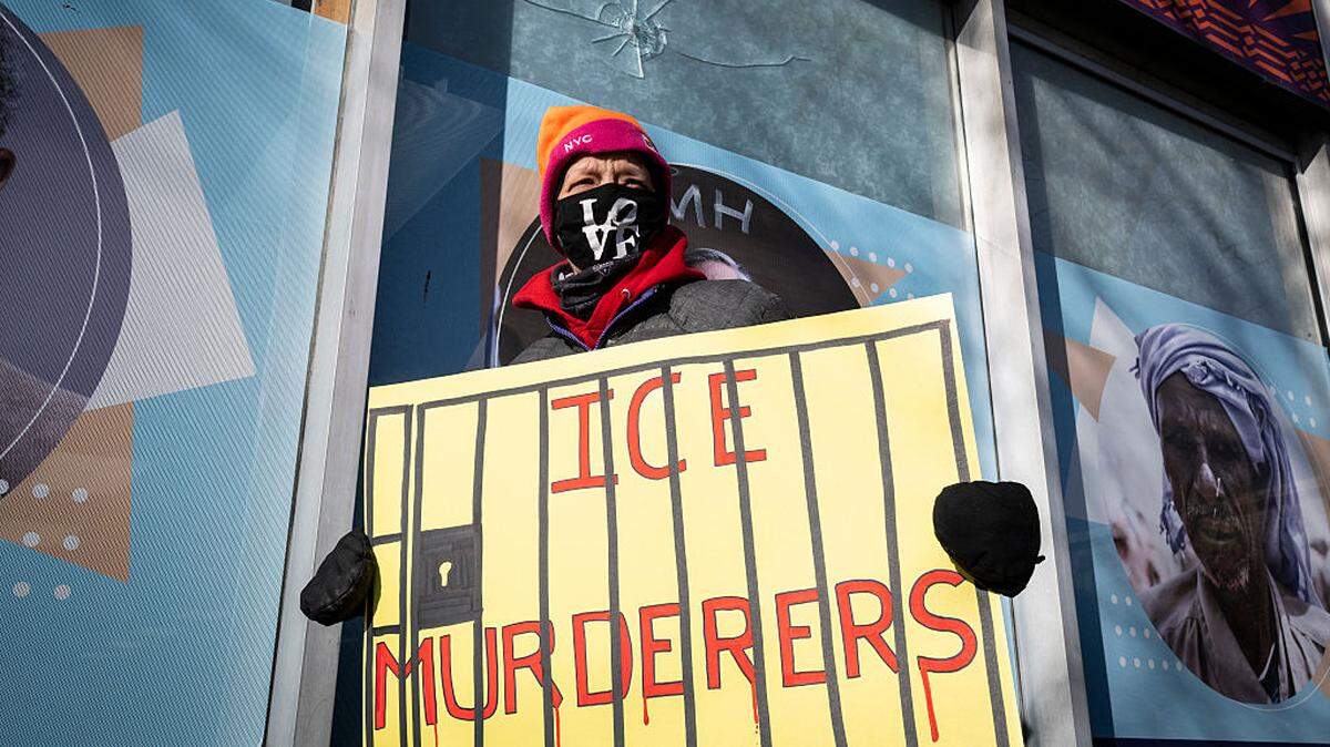 Sue, una mujer que llegó a Minneapolis desde Chicago para unirse a las protestas contra el ICE, lleva un cartel que dice “ICE, asesinos”, frente a unos paneles de vidrio que muestran dos orificios de bala, el lunes 26 de enero de 2026. Según el dueño del negocio, estos orificios fueron causados cuando Alex Pretti fue abatido a tiros por agentes federales en Minneapolis, Minnesota, el sábado 24 de enero de 2026.