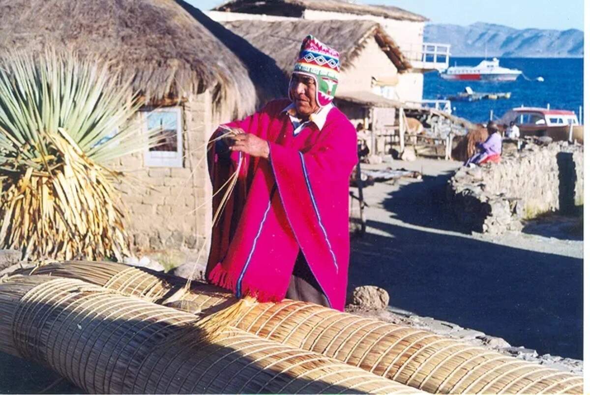 Un indígena construyendo una balsa de totora.