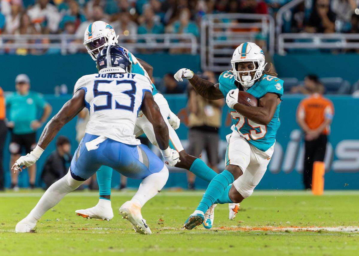 Miami Dolphins running back Jaylen Wright (25) runs with the football as Tennessee Titans linebacker Ernest Jones IV (53) defends in the first half of their NFL game at Hard Rock Stadium on Monday, Sept. 30, 2024, in Miami Gardens, Fla.