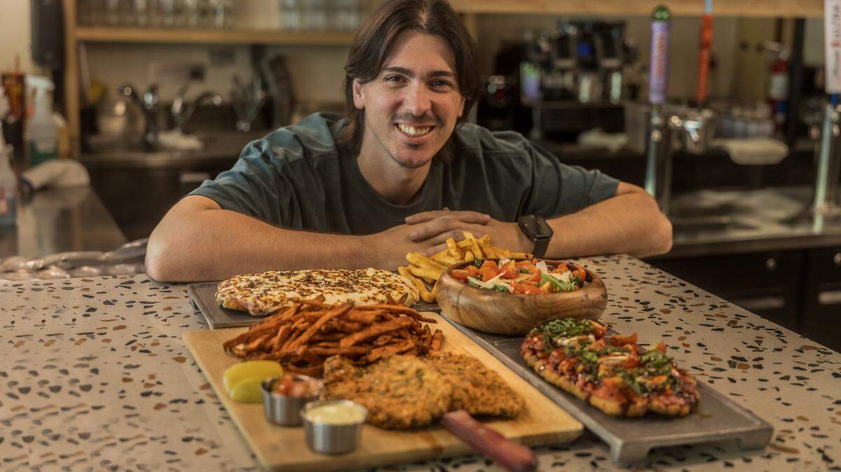 Manager Lucas Almiron displays several dishes including, from left- a New York Strip Milanesa, a Milanesa Napolitana, and a Chicken Milanesa Margherita, from the menu at La Casa de La Milanesa located in the Midtown area in Miami, on Tuesday, May 26, 2026.