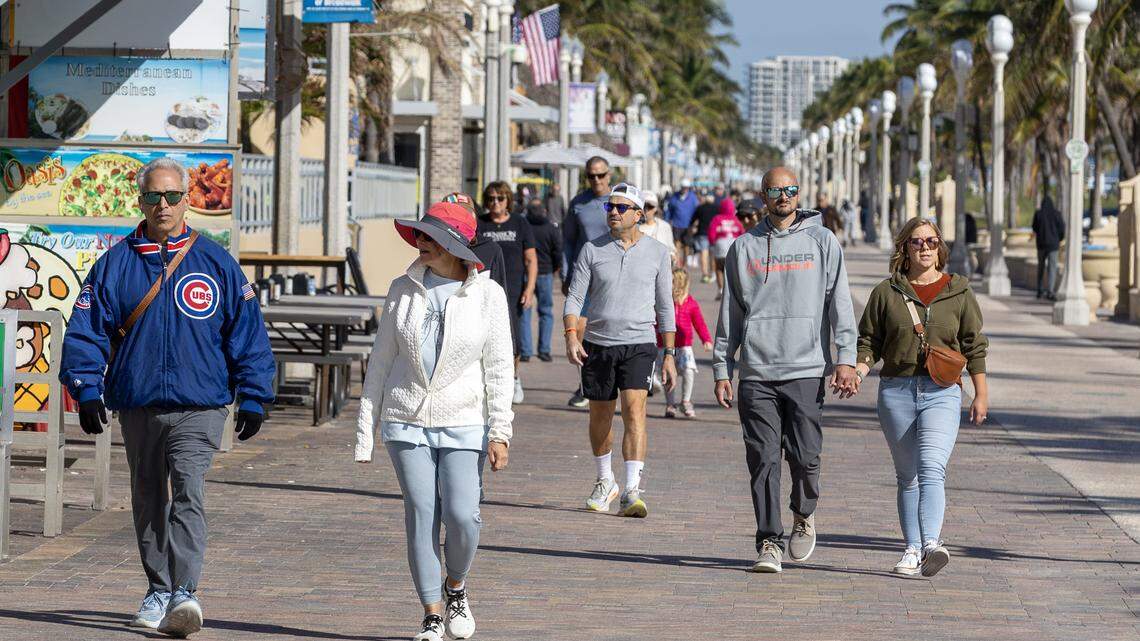 Personas abrigadas contra el frío recorren el Hollywood Beach Broadwalk el martes 11 de noviembre de 2025 en Hollywood, Florida, mientras un frente ártico trajo temperaturas más bajas de lo habitual al sur de Florida.