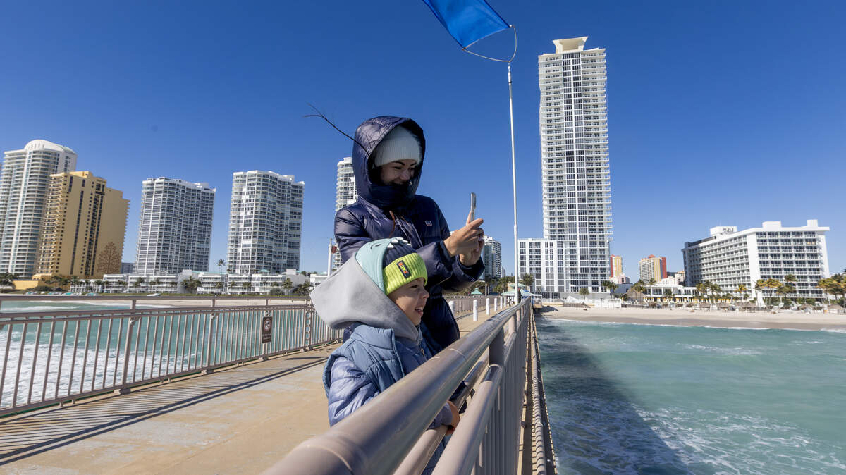La residente del sur de Florida Stephanie DeFrancesco corre junto a su hijo, Ari Sella, bien abrigado contra el frío, en el muelle de pesca de Newport en Sunny Isles Beach, Florida, el domingo 1 de febrero de 2026.