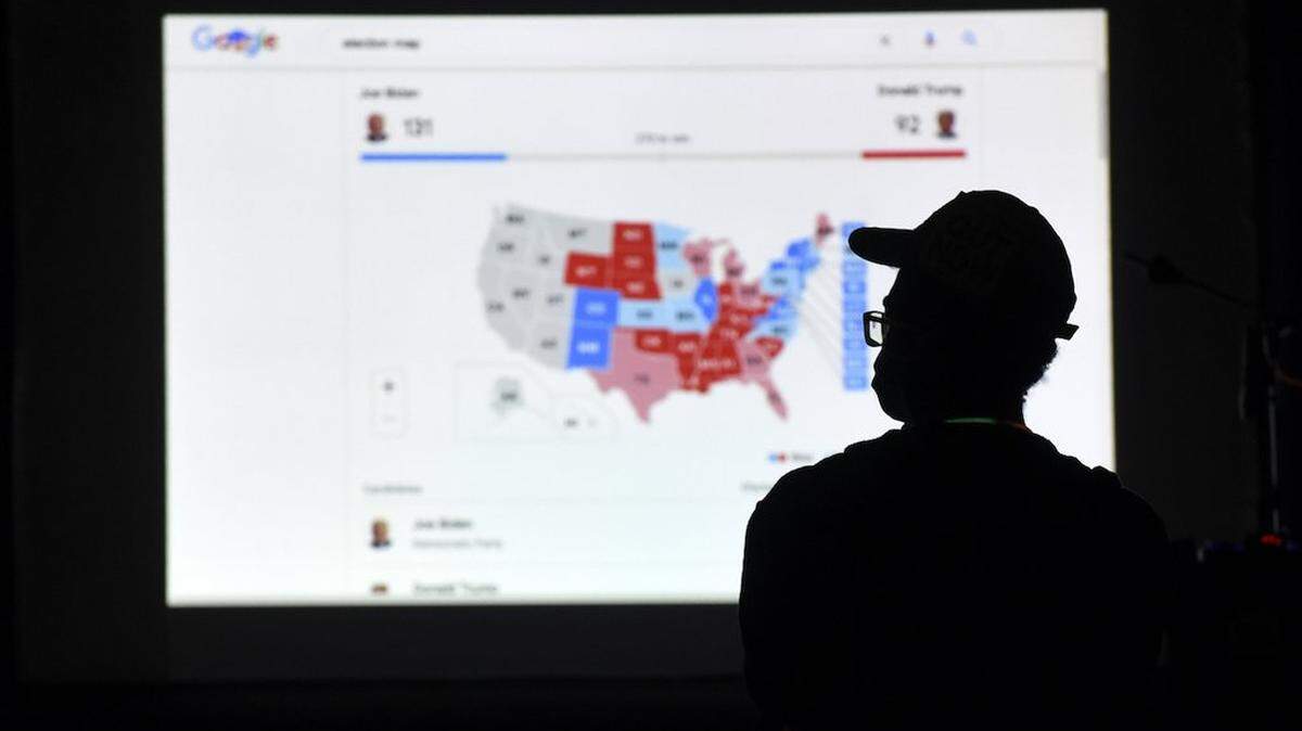 Un hombre mira los resultados en una pantalla la noche de las elecciones en Independence Mall en Filadelfia el 3 de noviembre de 2020.
