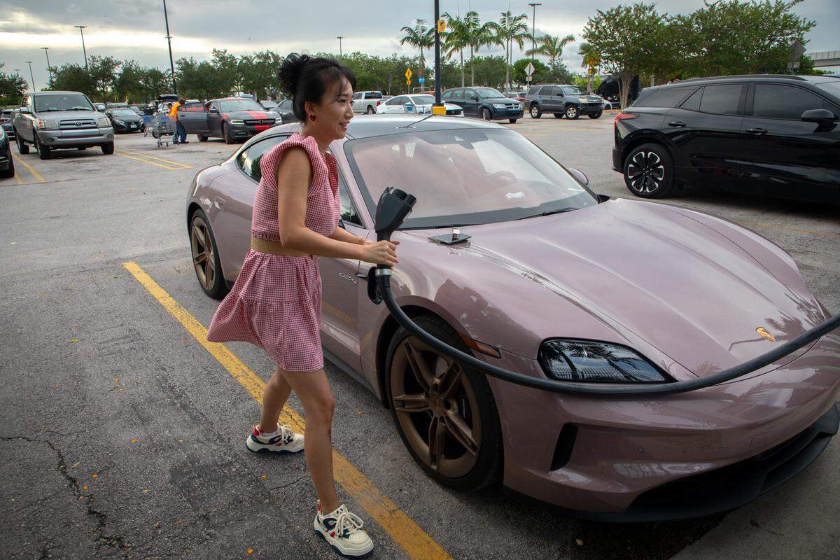 Tang P. conecta su Porsche Taycan rosa en un puerto de carga para vehículos eléctricos en el estacionamiento de Walmart en Hialeah el viernes 23 de agosto. Tang tenía dos autos delante de ella en la fila esperando para usar una de las cinco bombas. 