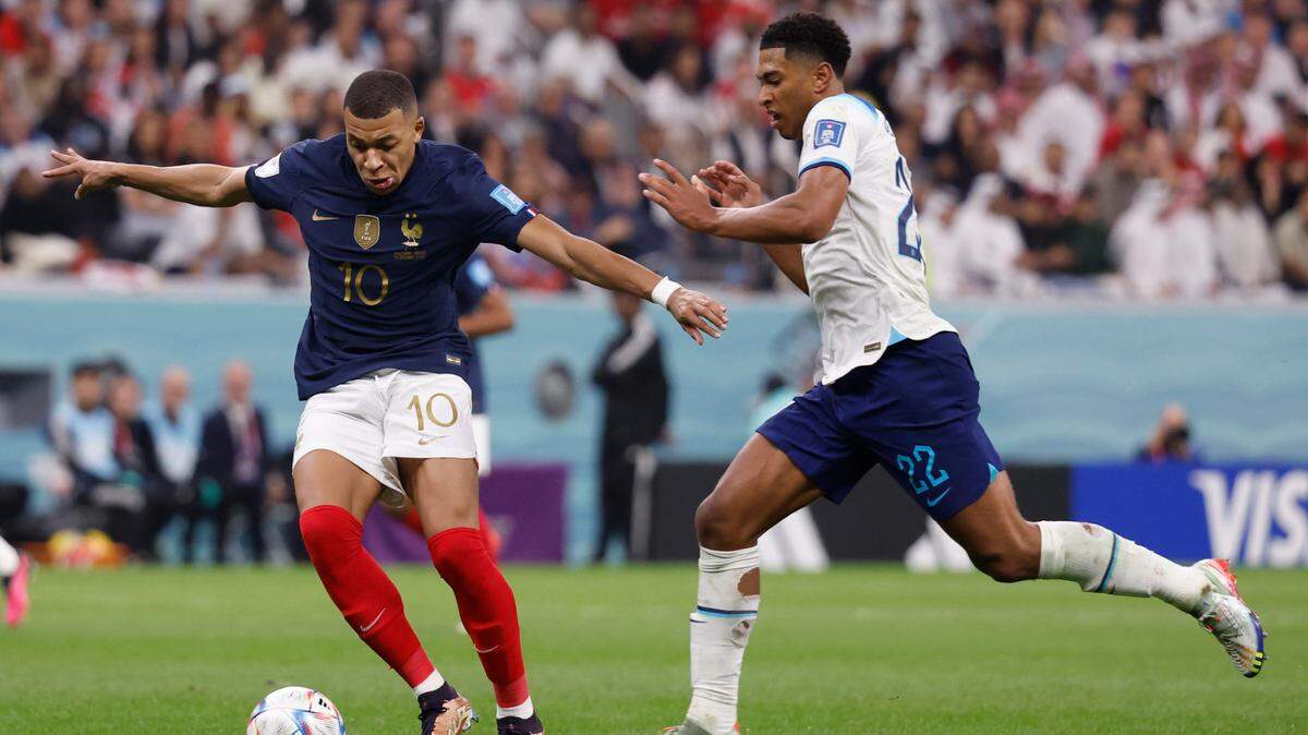 El delantero francés Kylian Mbappé (izq.) controla el balón frente al centrocampista inglés Jude Bellingham, en la segunda mitad del partido de cuartos de final de la Copa Mundial de la FIFA, celebrado el 10 de diciembre de 2022, en Al Khor, Catar.
