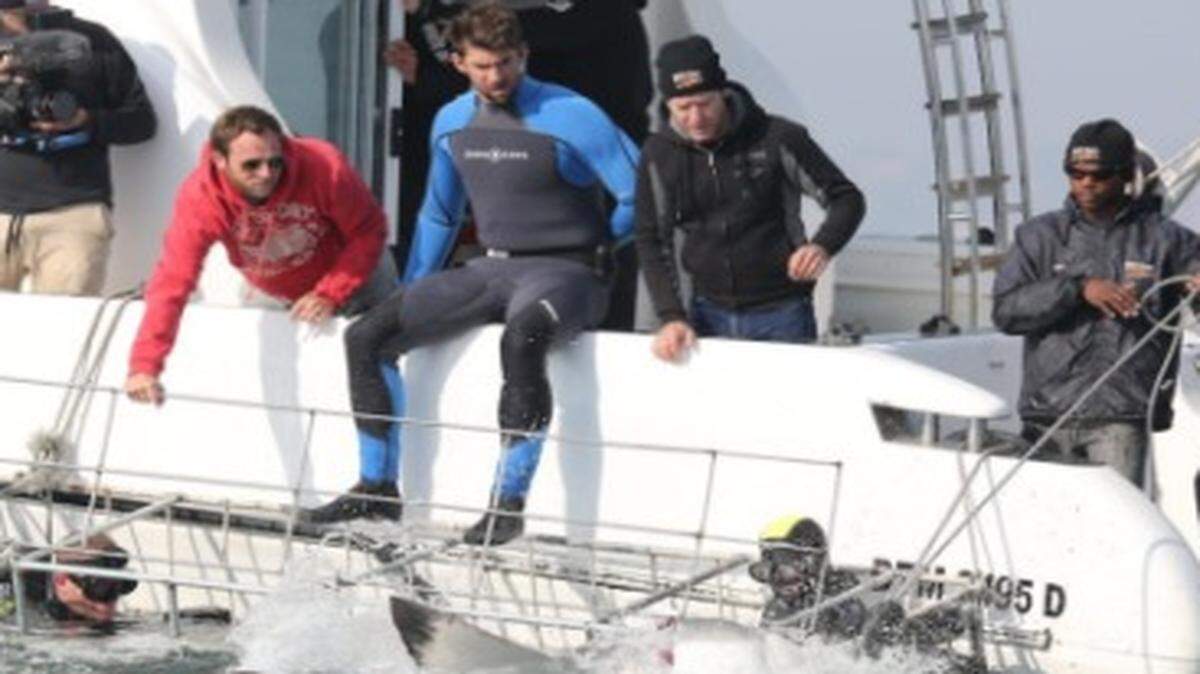 La leyenda olímpica estadounidense Michael Phelps (centro) tuvo uno de los “grandes desafíos” de su carrera al nadar contra un tiburón blanco para el canal de televisión Discovery en Español.
