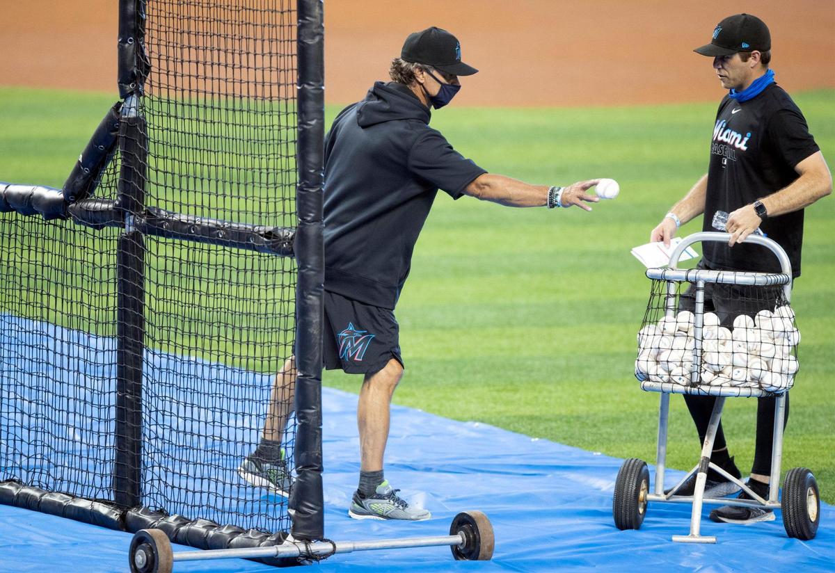 El manager de los Marlins, Don Mattingly, pone una pelota a la canasta en la práctica de bateo durante el primer día del campamento de entrenamiento de los Marlins en Marlins Park el viernes 3 de julio de 2020.