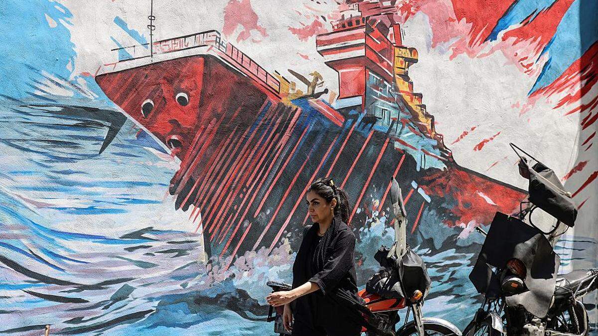 Una mujer iraní pasa frente a un mural antiestadounidense y antiisraelí en la capital, Teherán, el domingo 10 de mayo de 2026.