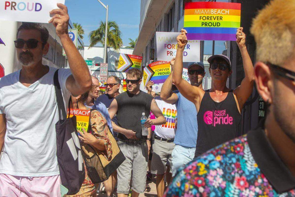 Manifestantes portando banderas arcoíris y carteles con las leyendas “Miami Beach Orgulloso por Siempre” y “No Serán Borrados” marchan durante la Marcha Orgulloso por Siempre en Ocean Drive, Miami Beach, Florida, el domingo 31 de agosto de 2025, después de que las autoridades estatales ordenaran la eliminación del cruce peatonal del Orgullo LGBTQ+ de la ciudad.