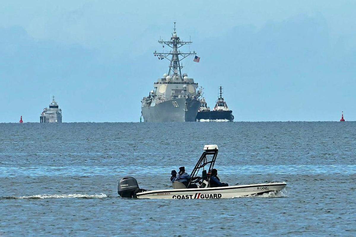 A speedboat of the Trinidad and Tobago Coast Guard patrols as the USS Gravely warship is seen at a distance from Port of Spain on October 26, 2025. The US warship will visit Trinidad and Tobago for joint exercises near the coast of Venezuela amid Washington's campaign against alleged drug traffickers in the region. (Photo by Martin BERNETTI / AFP) (Photo by MARTIN BERNETTI/AFP via Getty Images)
